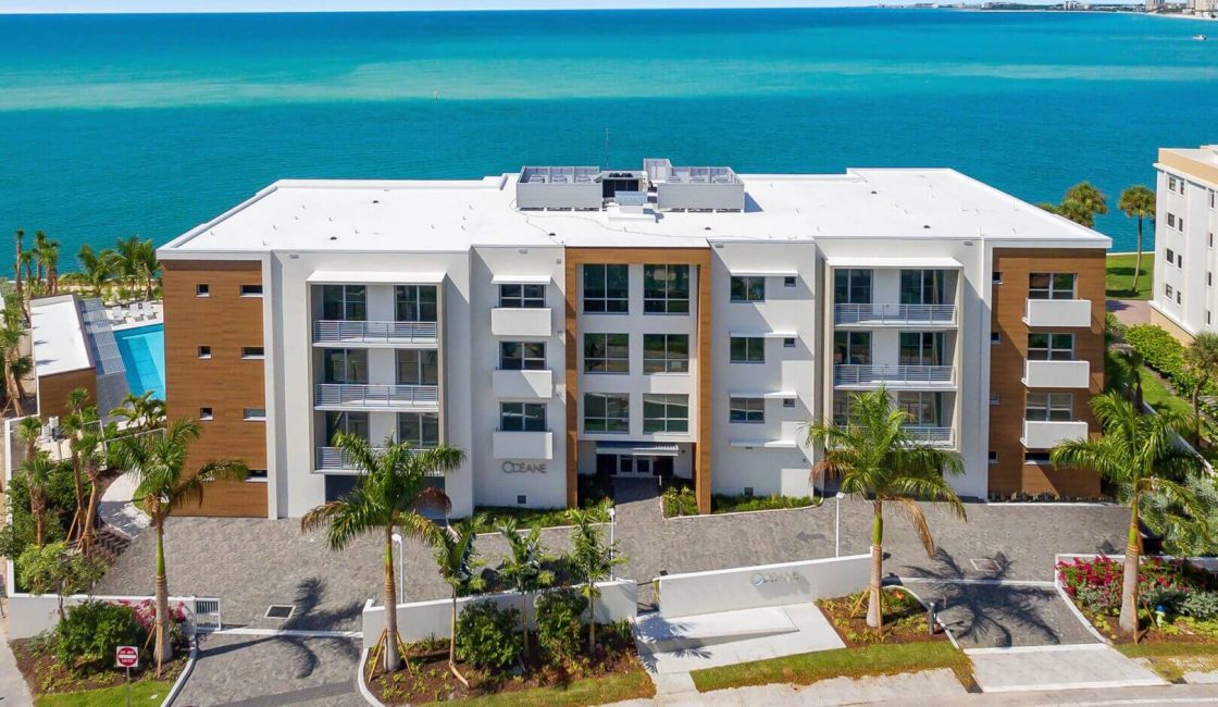 A building with a view of the ocean and palm trees.