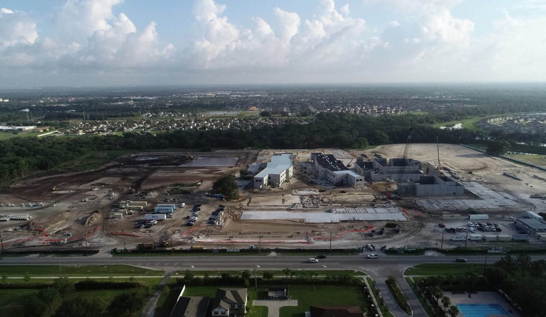 A large building under construction with many trees in the background.