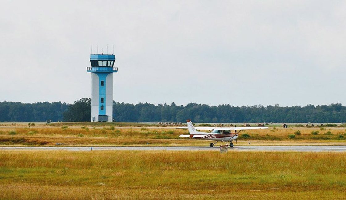 A plane is on the runway near an air traffic control tower.