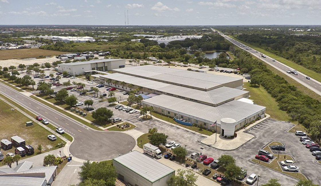An aerial view of a large building with cars parked in front.