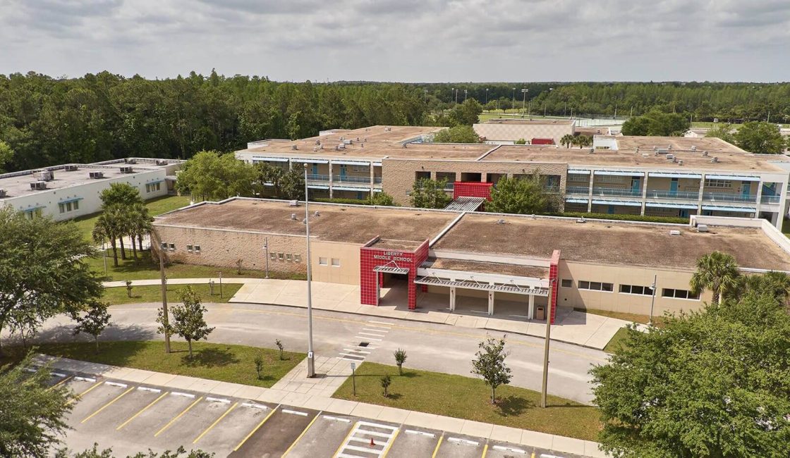 An aerial view of a large building with trees in the background.