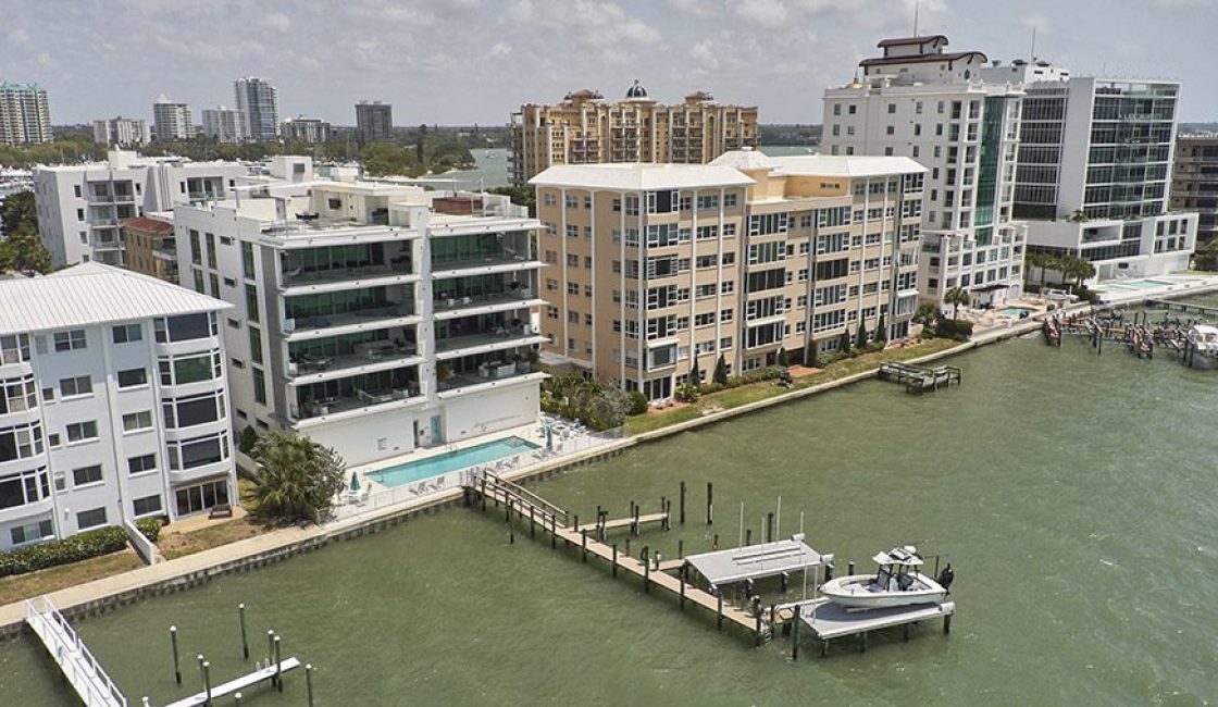 A dock with boats in the water near some buildings.