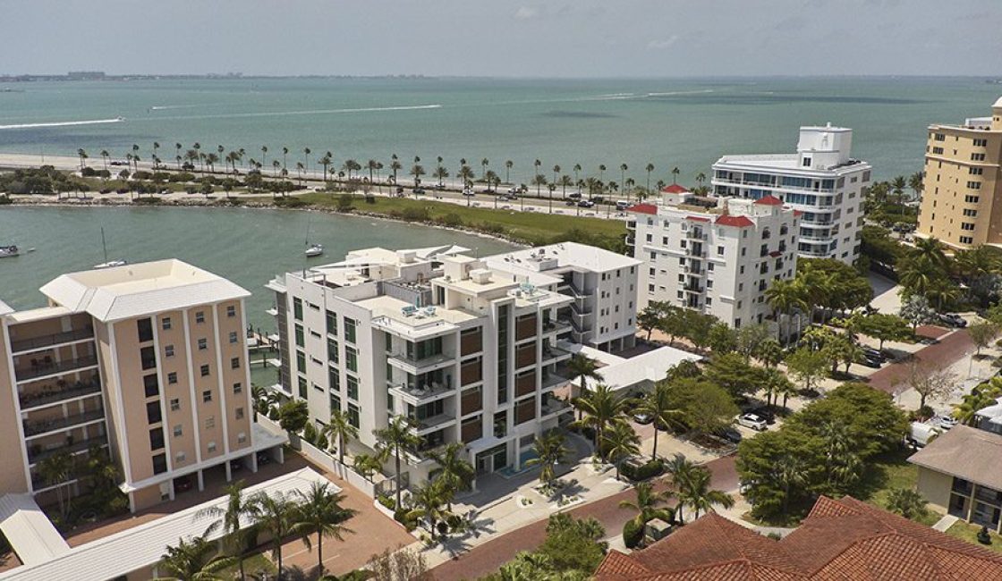 A view of the water from above shows palm trees, buildings and an ocean.