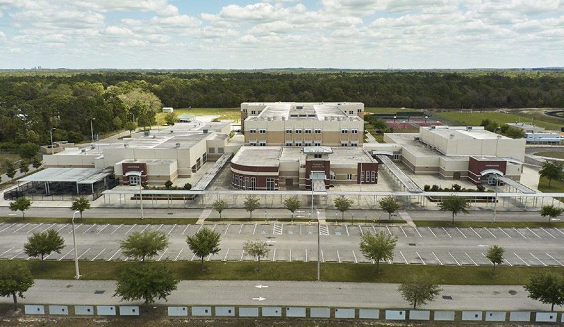 An aerial view of a large building with trees in the background.
