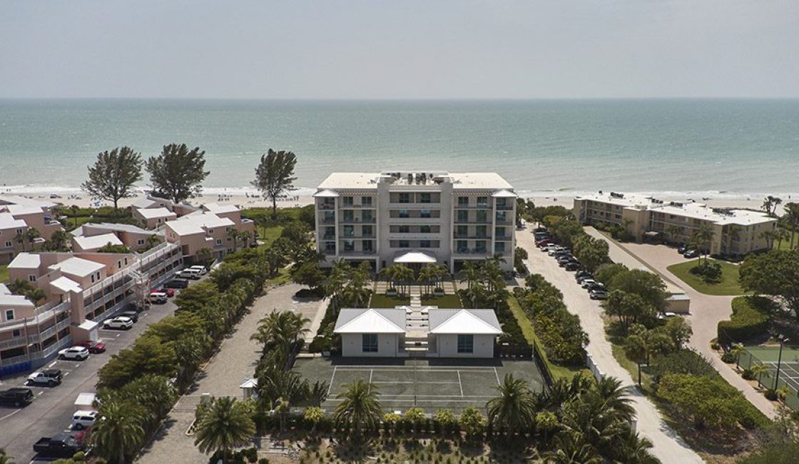 A hotel with tennis courts and a beach in the background.