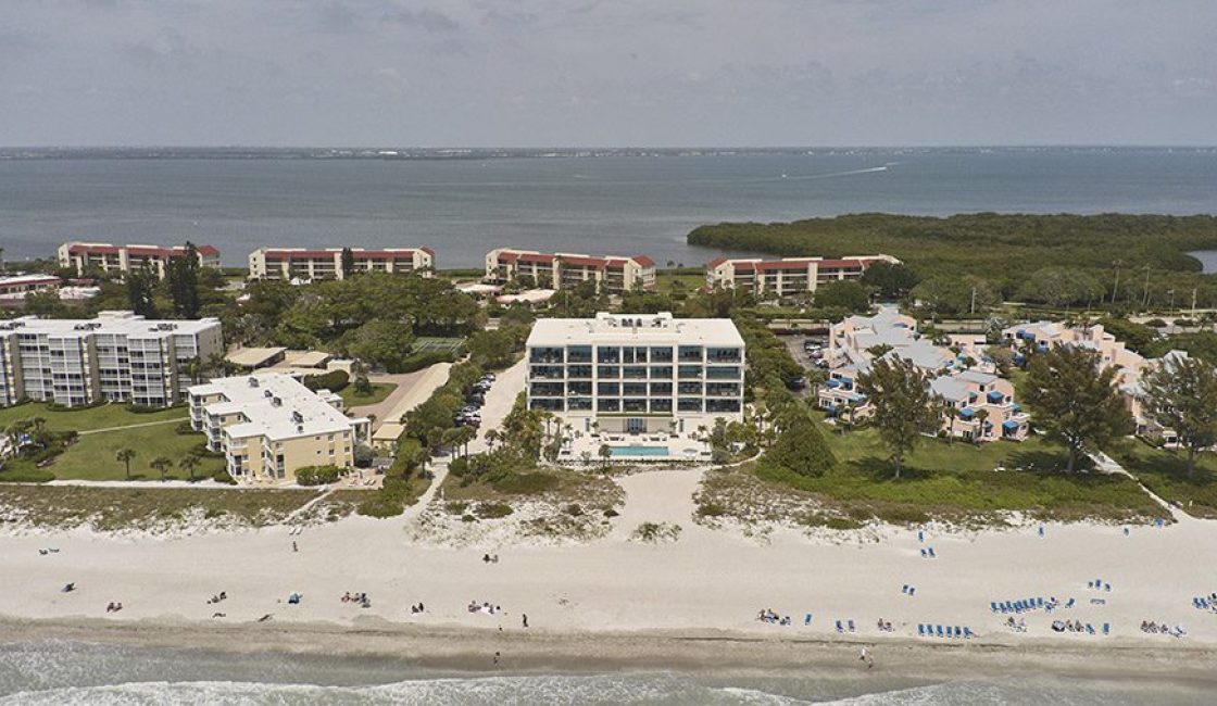A beach with many people on it and buildings in the background