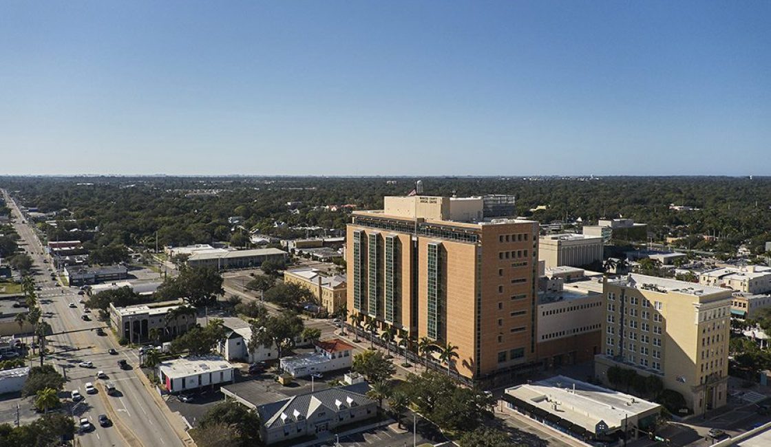 An aerial view of a city with buildings and cars driving down the road.