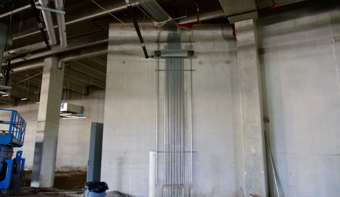 A large white wall with a metal pipe hanging from it.