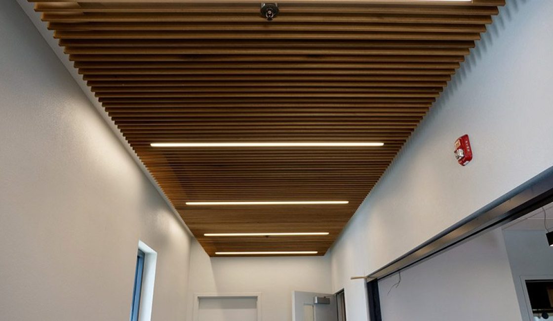 A hallway with wooden ceiling and white walls.