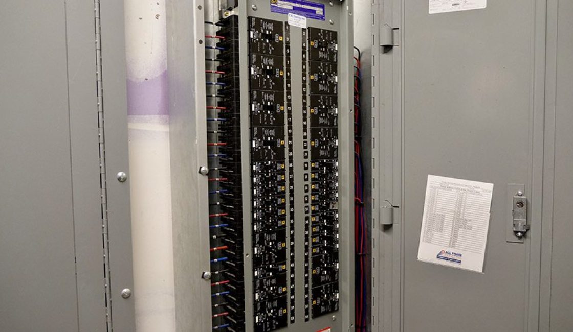 A large electrical panel with many wires hanging from it.