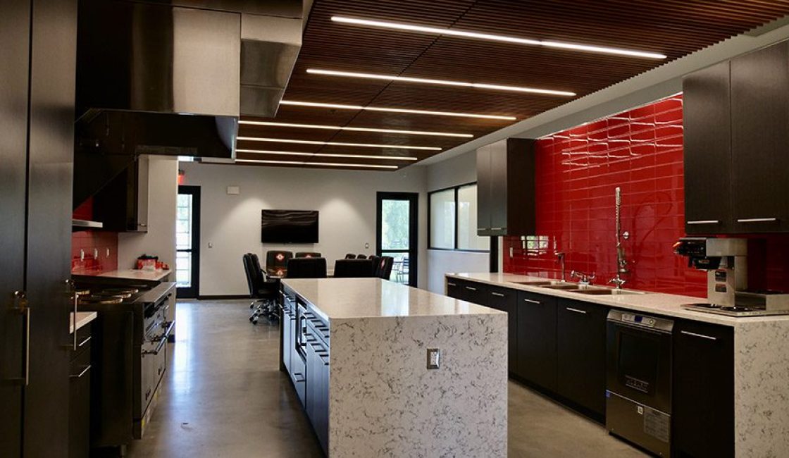 A kitchen with a large island and red wall.