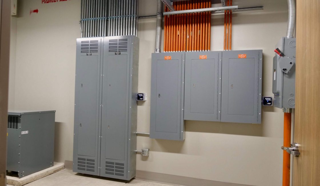 A room with two electrical boxes and one of them has orange stripes on the wall.