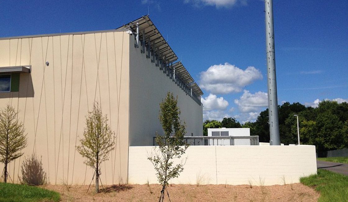 A building with a fence and trees in the background