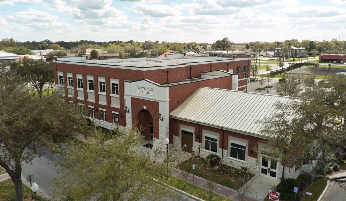 An aerial view of a building with a tree in front.